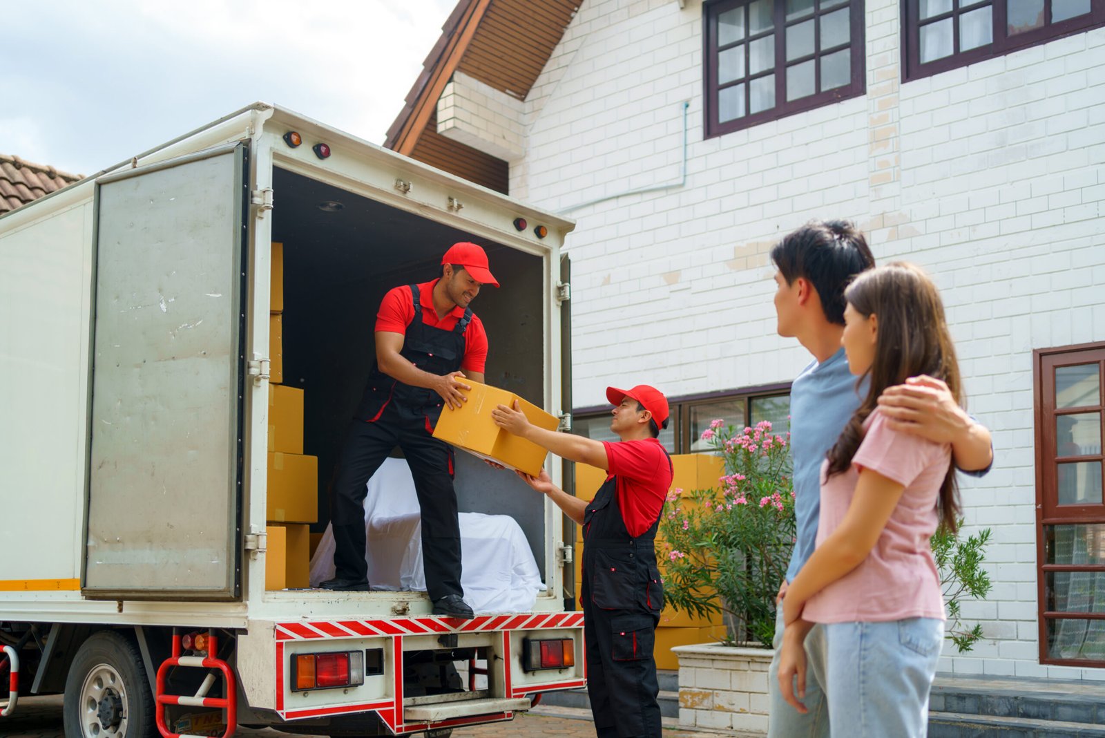 asian couple watching workers move their new home scaled